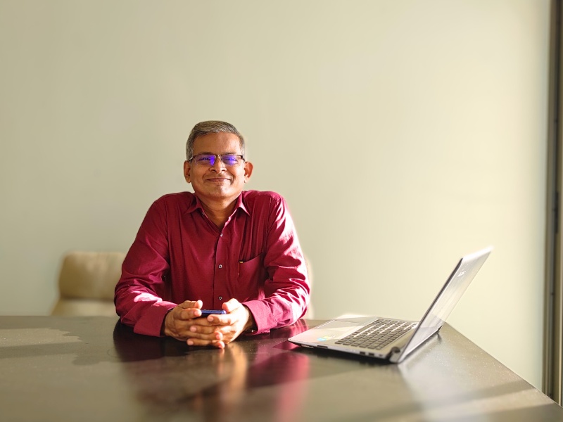 Archiradhi Communications founder sitting in front of a laptop looking towards the camera and smiling.